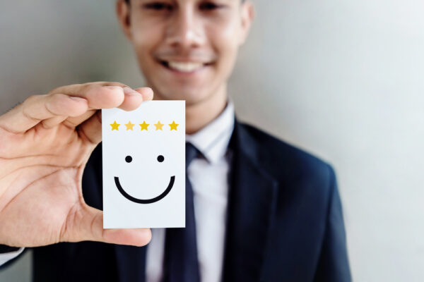 Man smiling holding a five star card.
