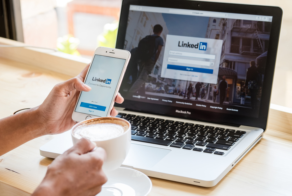LinkedIn login page on mobile device and laptop screen.