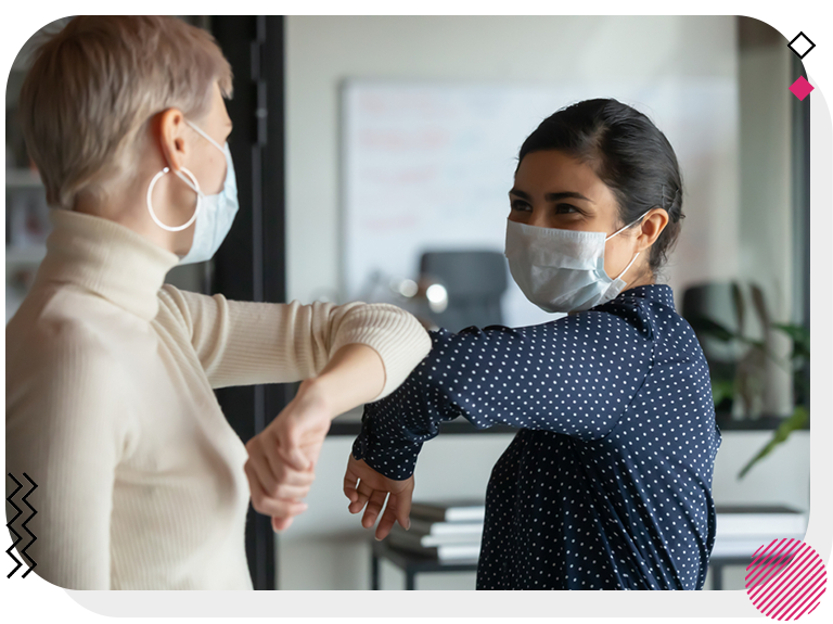 Women shaking hands with their elbows while wearing masks.
