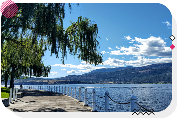 Boardwalk in Kelowna with an overhanging tree and a hill in the background