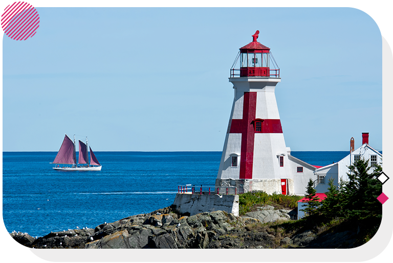 White lighthouse with red details on top of rocks with a sailboat in the background